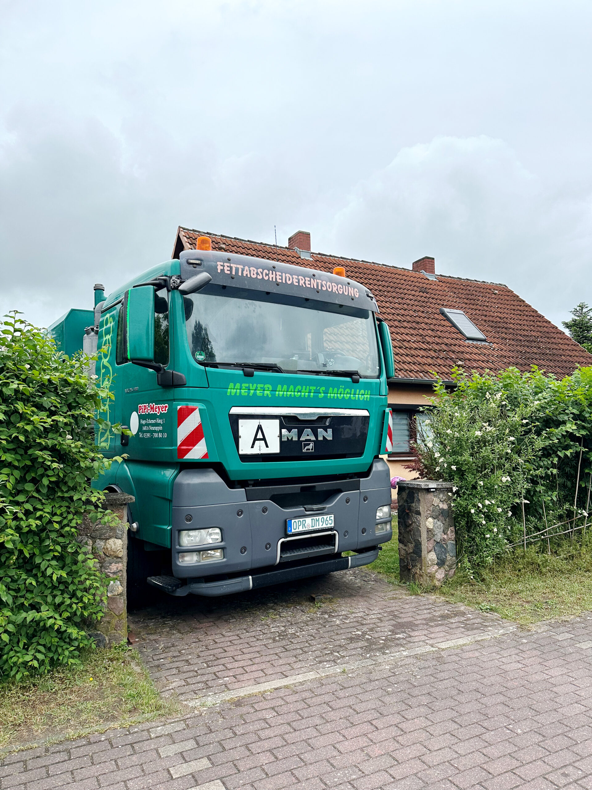 Sauwagen fährt rückwärts auf die Hofeinfahrt um anschließend den Teich zu reinigen